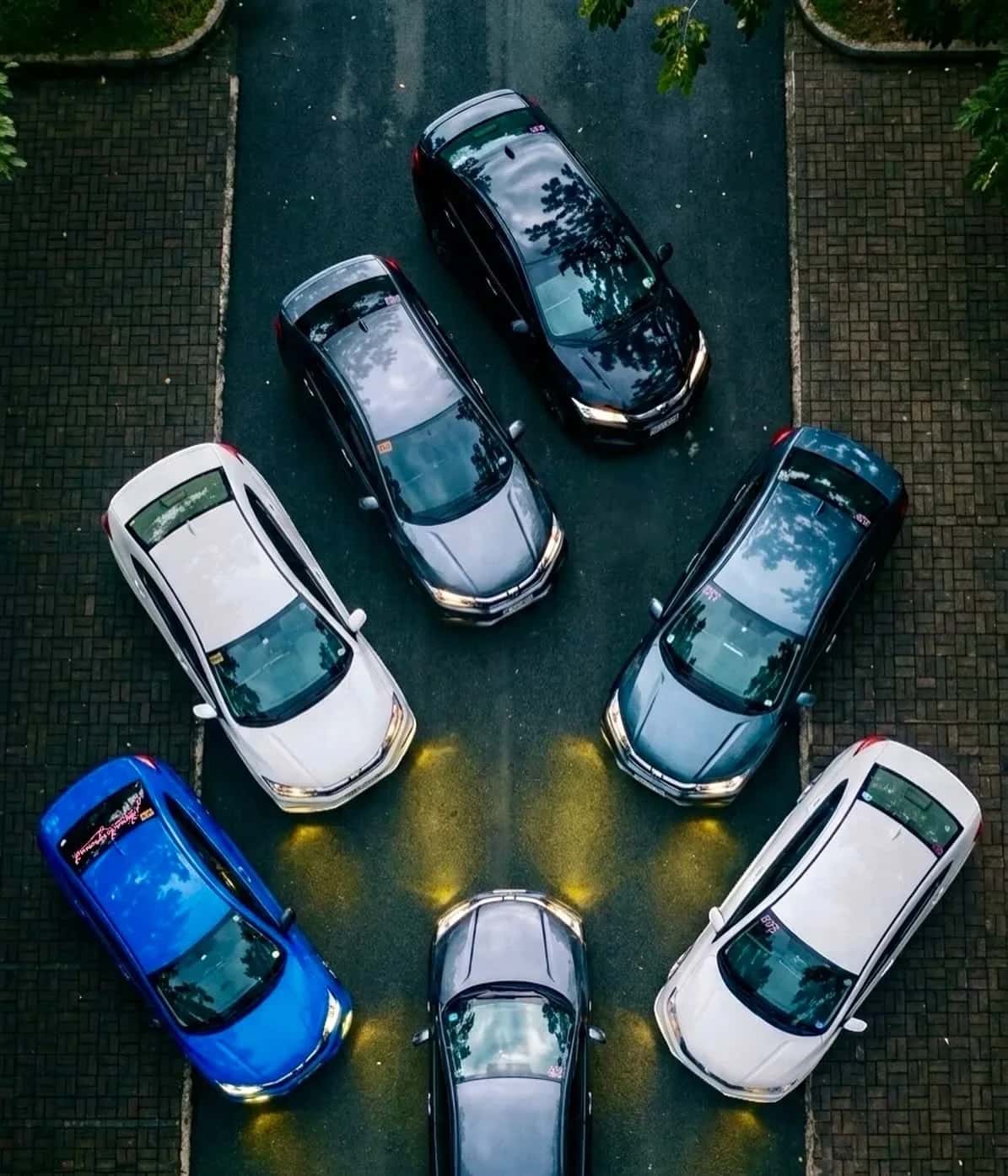 Aerial view of seven Honda Citys parked in a star formation, headlights pooling at the centre